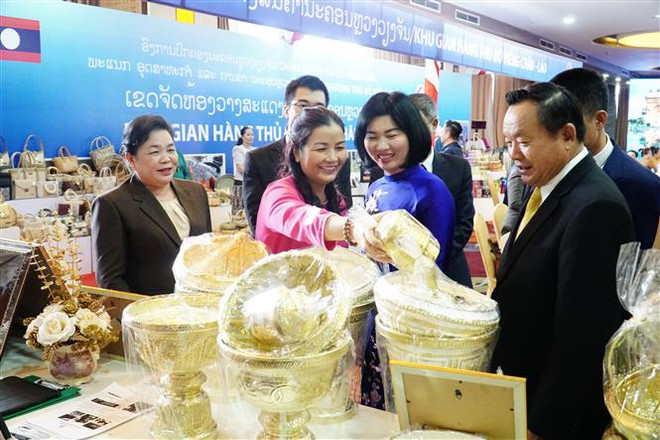 Đoàn đại biểu Hội đồng Nhân dân thành phố Hà Nội tham quan gian trưng bày hàng hóa. (Ảnh: Đỗ Bá Thành/TTXVN) Tăng cường hợp tác giữa HĐND hai thủ đô Hà Nội và Vientiane ảnh 3