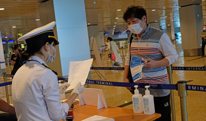 Lực lượng chức năng kiểm tra khai báo y tế của những hành khách đáp chuyến bay từ Hàn Quốc đến sân bay Cam Ranh trong chiều 25/2. (Ảnh: Nguyễn Dũng/TTXVN) COVID-19: Tạm dừng việc miễn visa cho công dân Hàn Quốc từ 29/2 ảnh 1