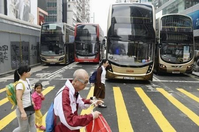 Xe buýt không thể di chuyển trên phố sau khi bị người biểu tình chọc thủng lốp tại Hong Kong, Trung Quốc ngày 12/11. (Nguồn: Kyodo/TTXVN) Chính quyền Hong Kong hối thúc chú ý sự an toàn của học sinh ảnh 1