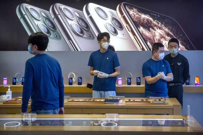 Nhân viên đeo khẩu trang trong một cửa hàng của Apple ở Bắc Kinh. (Nguồn: AP) Apple thừa nhận không đạt được mục tiêu doanh thu vì COVID-19 ảnh 1
