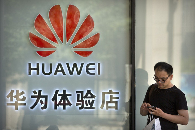Một người đang sử dụng điện thoại bên ngoài cửa hàng Huawei ở Bắc Kinh. (Nguồn: AP) Huawei thưởng lớn cho nhân viên giúp hãng vượt qua cấm vận của Mỹ ảnh 1
