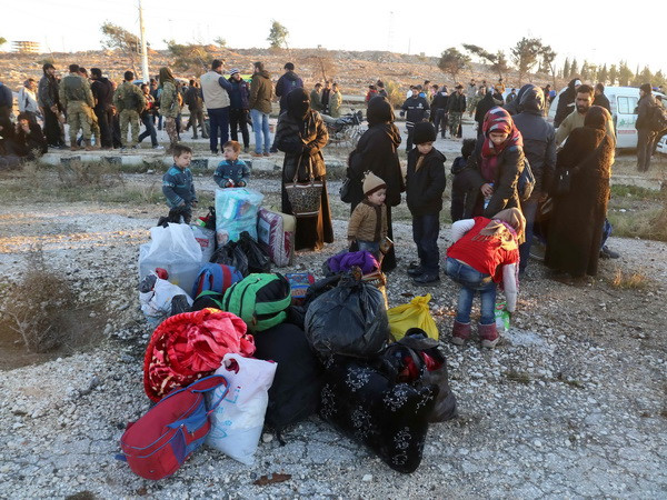 Nhân viên cứu hộ hỗ trợ người Syria sơ tán khỏi khu vực do phiến quân chiếm giữ ở Aleppo tới khu vực Khan al-Assal, phía tây thành phố ngày 15/12. (Nguồn: AFP/TTXVN) EU cam kết thúc tăng cường nỗ lực cứu trợ nhân đạo tại Syria ảnh 1