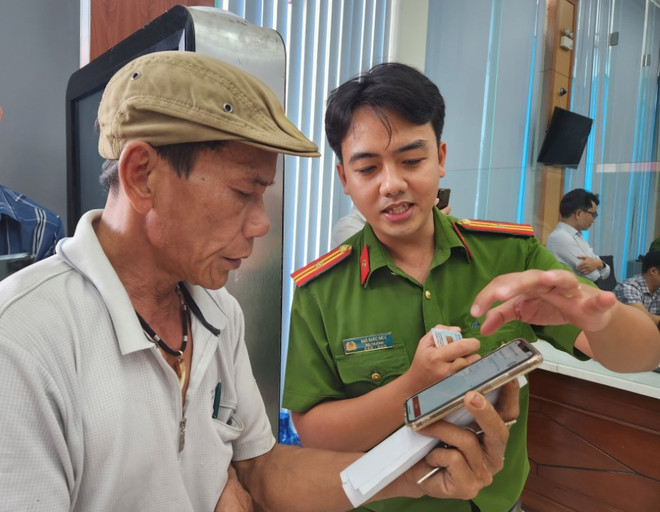 Cán bộ công an hướng dẫn người dân thao tác xin cấp phiếu lý lịch tư pháp trên ứng dụng VNeID. (Ảnh: Mai Trang/TTXVN) ly lich tu phap 2.jpg