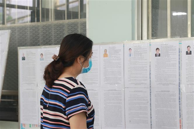 Cử tri tại Khu cách ly tập trung tại Trung tâm Y tế quận Gò Vấp nghiên cứu thông tin người ứng cử. (Ảnh: Đinh Hằng/TTXVN) Cử tri TP.HCM với những lá phiếu trách nhiệm và niềm tin ảnh 1