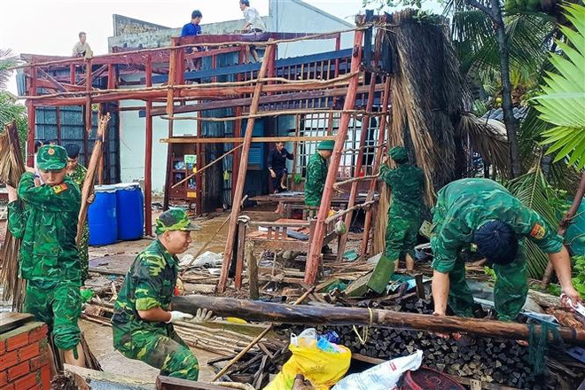 Bộ đội Biên phòng Cà Mau giúp người dân xã Khánh Hội, huyện U Minh dựng lại nhà bị sập do ảnh hưởng cơn bão số 1. (Ảnh: TTXVN phát) Cà Mau, Vĩnh Long chịu nhiều thiệt hai do mưa bão, dông lốc ảnh 1