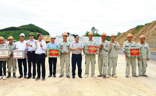Thủ tướng Phạm Minh Chính tặng quà cho công nhân thi công Dự án xây dựng tuyến đường Đông-Tây. (Ảnh: Dương Giang/TTXVN) thu_tuong_pham_minh_chinh_tham_co_so_san_xuat_du_an_giao_thong_trong_diem_tai_ninh_binh6.jpg