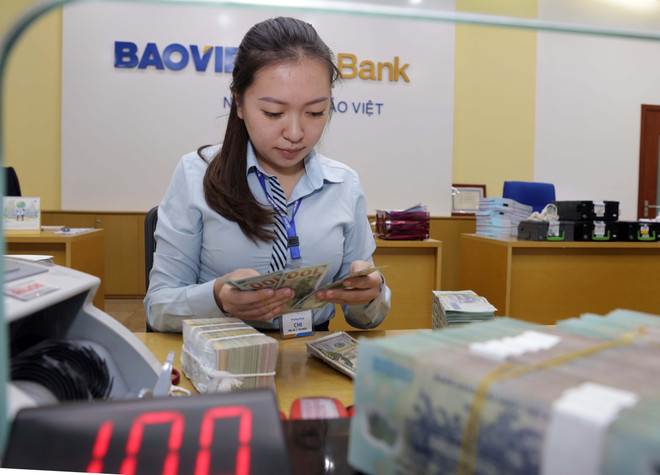 Hoạt động nghiệp vụ tại Ngân hàng TMCP Bảo Việt. (Ảnh: Trần Việt/TTXVN) Tác động từ chính sách của Fed với thị trường tài chính Việt Nam ảnh 1
