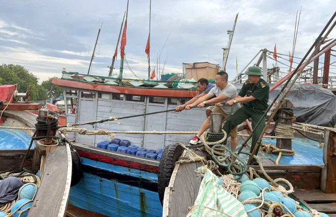 Lực lượng biên phòng hỗ trợ người dân chằng dây tàu thuyền trước khi bão đỗ bộ. (Ảnh: Nguyễn Nam/TTXVN) Bão số 2 di chuyển xuống Vịnh Bắc Bộ có xu hướng suy yếu về cường độ ảnh 3