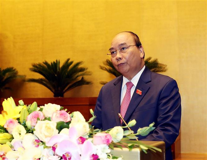 Thủ tướng Nguyễn Xuân Phúc đọc báo cáo của Chính phủ. (Ảnh: Trọng Đức/TTXVN) Quốc hội bàn về duy trì ổn định kinh tế vĩ mô vững chắc hơn ảnh 1