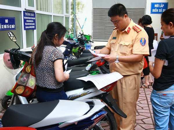 Công an quận Hai Bà Trưng, Hà Nội làm thủ tục đăng ký đăng ký xe môtô điện, xe máy điện cho nhân dân trước ngày 1/7/2016. (Ảnh: Doãn Tấn/TTXVN) Hướng dẫn người dân làm thủ tục đăng ký sang tên phương tiện ảnh 1