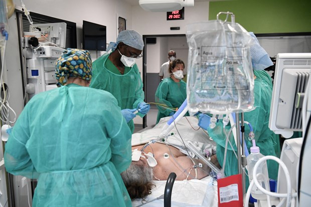 Nhân viên y tế điều trị cho bệnh nhân COVID-19 tại bệnh viện ở Saint-Denis, ngoại ô Paris, Pháp, ngày 29/12/2021. (Ảnh: AFP/TTXVN) Dự báo thế giới năm 2022: Sáu mối lo lớn tác động toàn cầu ảnh 1