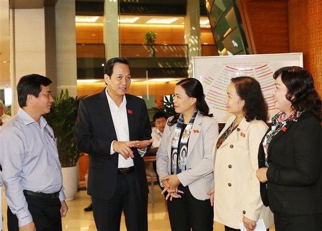 Các đại biểu Quốc hội trao đổi trong giờ nghỉ giải lao. (Ảnh: Trọng Đức/TTXVN) Hoàn thiện hệ thống văn bản về phòng, chống thiên tai và đê điều ảnh 2