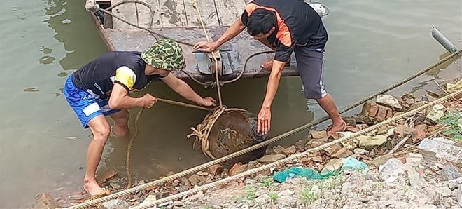 Lực lượng chức năng tiến hành trục vớt quả bom trên sông Đuống. (Ảnh TTXVN phát) Hà Nội: Phát hiện, xử lý một quả bom dài 2m ở sông Đuống ảnh 1