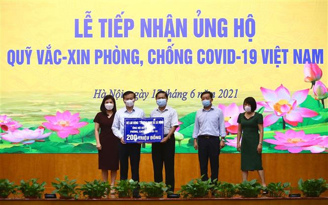 Thứ trưởng Bộ Lao động-Thương binh và Xã hội Lê Tấn Dũng (giữa) trao ủng hộ Quỹ cho Phó Tổng giám đốc kho bạc nhà nước Nguyễn Quang Vinh. (Ảnh: Hoàng Hiếu/TTXVN) Nhiều cơ quan, doanh nghiệp, cá nhân tiếp tục ủng hộ phòng, chống dịch ảnh 2