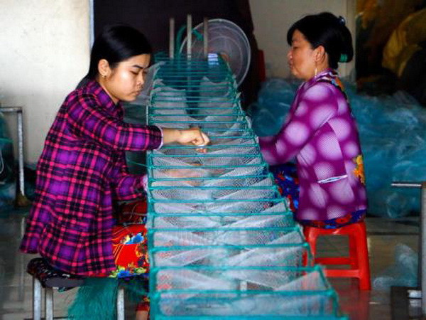 Người dân làng lưới tất bật sản xuất hàng phục vụ nhu cầu đánh bắt thủy sản trong mùa lũ. (Ảnh: Thanh Liêm/TTXVN) Đồng bằng sông Cửu Long mùa nước nổi: Ngày mùa ở các làng nghề ảnh 1
