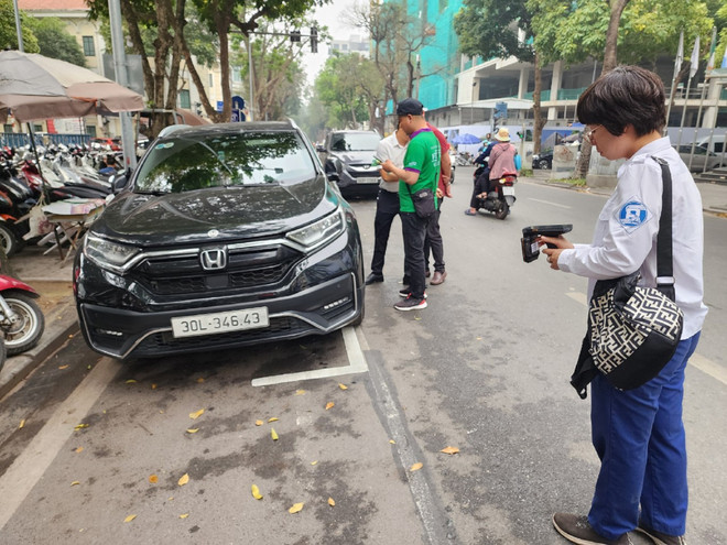 Tại điểm trông giữ xe dưới lòng đường, nhân viên trông giữ sẽ dùng thiết bị cầm tay để nhận diện thẻ Etag định danh gắn trên phương tiện. (Ảnh: Việt Hùng/Vietnam+) vnp_diem do 6.jpg