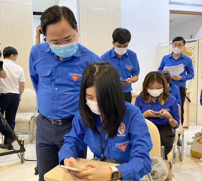 Ủy viên Trung ương Đảng-Bí thư thứ nhất Trung ương Đoàn Nguyễn Anh Tuấn quan sát các bạn đoàn viên, thanh niên cài đặt ứng dụng để làm bài thi trên điện thoại. (Ảnh: Hồng Giang/TTXVN) Hội thi Olympic các môn Khoa học Mác-Lênin và Tư tưởng Hồ Chí Minh ảnh 2