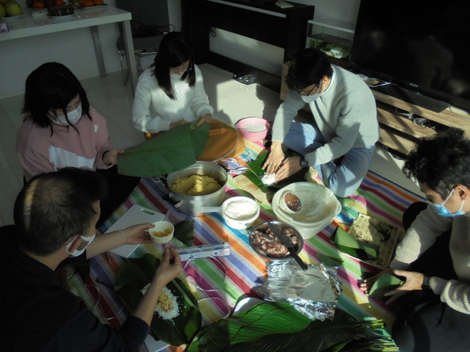 Gia đình anh Đỗ Minh Thịnh và bạn bè gói bánh chưng để chuẩn bị đón Tết. (Ảnh: Phạm Tuân/TTXVN) Tết gắn kết của các gia đình trẻ người Việt ở đất nước Mặt trời mọc ảnh 1