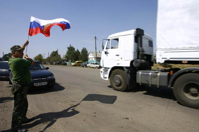 Một người dân Ukraine phất cờ Nga đón đoàn xe viện trợ (Nguồn: AFP) Đoàn xe nhân đạo thứ 4 của Nga tới miền Đông Nam Ukraine ảnh 1