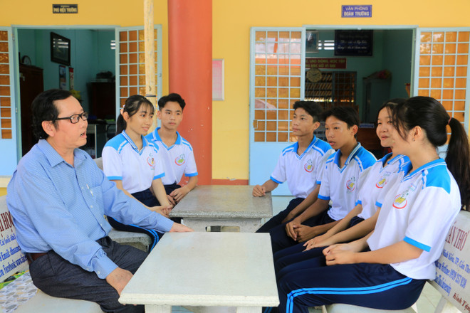 Thầy Nguyễn Minh Thiện với các em học sinh Trường Trung học Phổ thông Trà Ôn. (Ảnh: Lê Thúy Hằng/TTXVN) Thầy Nguyễn Minh Thiện và hành trình "gieo chữ" cho học sinh vùng sâu ảnh 1