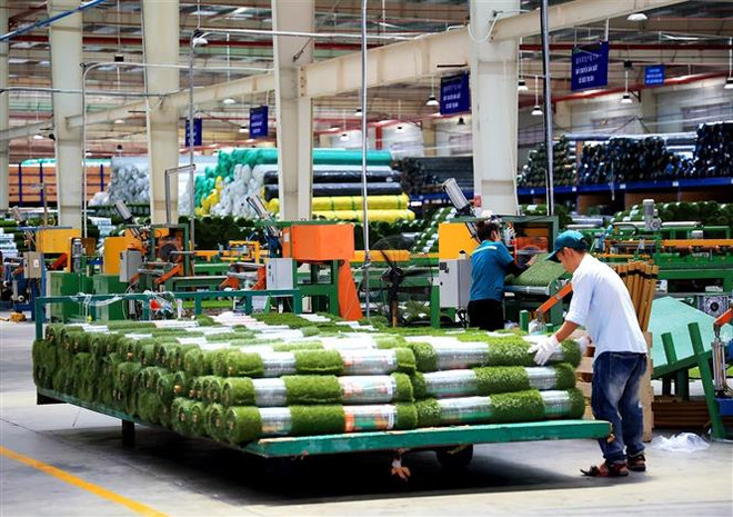 Công nhân làm việc trong nhà máy sản xuất thảm cỏ nhân tạo, Công ty TNHH CCGrass Việt Nam, Khu công nghiệp Phước Đông, huyện Gò Dầu, Tây Ninh. (Ảnh: Hồng Đạt/TTXVN) “Quả ngọt” từ những quyết sách và điều hành quyết liệt, linh hoạt ảnh 3
