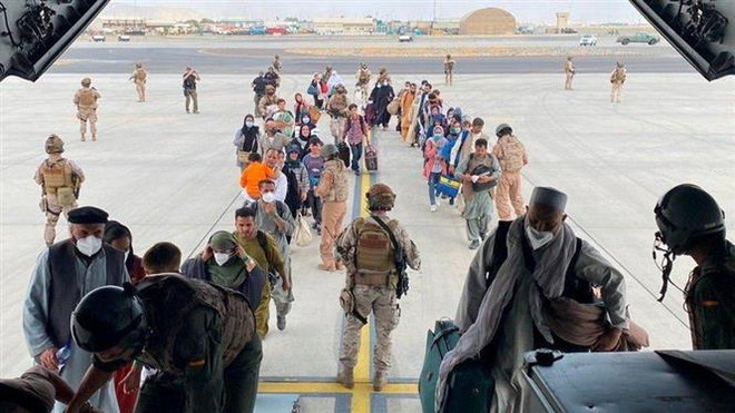 Người dân được lực lượng an ninh hỗ trợ lên máy bay sơ tán khỏi Afghanistan, tại sân bay quốc tế ở Kabul. (Ảnh: REUTERS/TTXVN) Đại sứ quán Anh để sót tài liệu về các cộng tác viên người Afghanistan ảnh 1