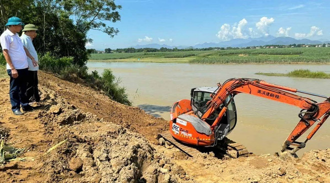 Chính quyền địa phương huy động máy xúc để hạ độ cao, tạo mái kè khắc phục tạm thời tình trạng sạt lở. (Ảnh: Việt Hoàng/TTXVN) ttxvn_sat lo bo song Chu (2).jpg