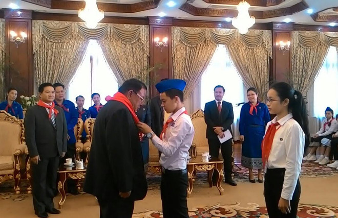 Một thiếu nhi tiêu biểu của Việt Nam đang quàng khăn đỏ cho Tổng Bí thư, Chủ tịch nước Lào Bounnhang Volachith. (Ảnh: Phạm Kiên/Vietnam+) Giới trẻ Việt-Lào cần cùng chung lòng vun đắp quan hệ song phương ảnh 1