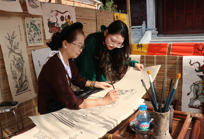 Du khách tìm hiểu tranh dân gian Đông Hồ tại chợ tranh. (Ảnh: Thanh Thương/TTXVN) TTXVN_3005tranhDongho2.jpg