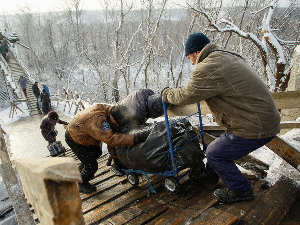 Người dân đi qua chốt kiểm soát giữa quân đội Ukraine và lực lượng đòi độc lập bằng chiếc thang gỗ thay thế cho chiếc cầu bị phá hủy trong một đợt giao tranh ở khu vực Luhansk ngày 16/12. (Nguồn: EPA/TTXVN) Nga và NATO tiếp tục bất đồng sâu sắc trong vấn đề Ukraine ảnh 1