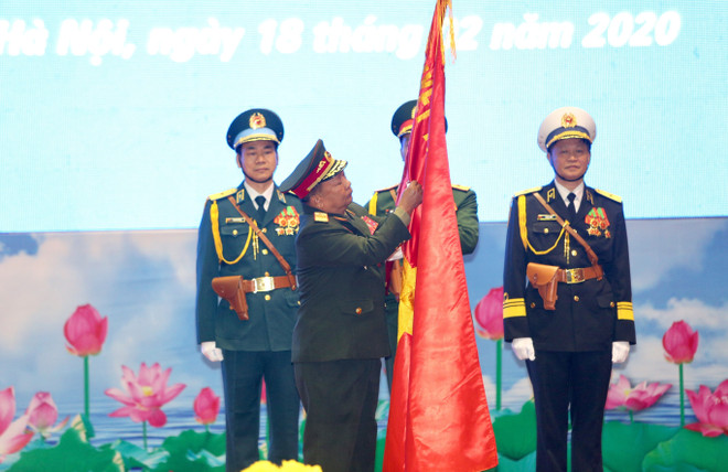 Đại tướng Chansamone Chanyalath, Bộ trưởng Bộ Quốc phòng CHDCND Lào gắn Huân chương Tự do hạng Nhất lên cờ truyền thống của Quân đội nhân dân Việt Nam. (Ảnh: Dương Giang/TTXVN) Trao Huân chương của Nhà nước Việt Nam và Lào cho các tập thể, cá nhân ảnh 2