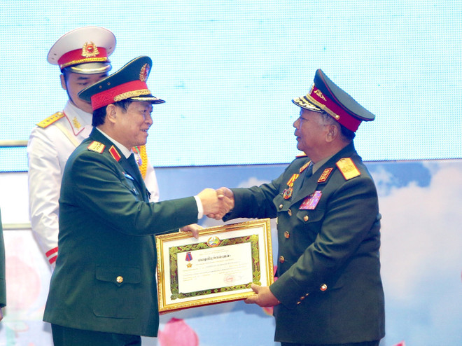 Đại tướng Chansamone Chanyalath, Bộ trưởng Bộ Quốc phòng CHDCND Lào trao Huân chương Tự do hạng Nhất cho Quân đội nhân dân Việt Nam. (Ảnh: Dương Giang/TTXVN) Trao Huân chương của Nhà nước Việt Nam và Lào cho các tập thể, cá nhân ảnh 3