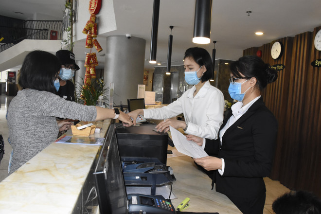 Nhân viên lễ tân khách sạn CAO Vũng Tàu đang tiến hành đo thân nhiệt cho du khách khi nhận phòng tại quầy lễ tân của khách sạn. (Ảnh: Ngọc Sơn/TTXVN) COVID-19 tiếp tục "giáng đòn" vào kỳ vọng phục hồi của khách sạn ảnh 1