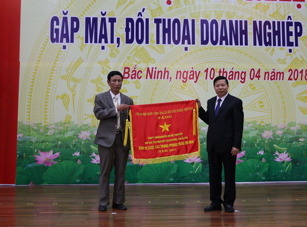 Bí thư Tỉnh ủy Bắc Ninh Nguyễn Nhân Chiến trao cờ thi đua của Chính phủ cho đơn vị có thành tích xuất sắc năm 2017. (Ảnh: Thanh Thương/TTXVN) Bắc Ninh đối thoại, tháo gỡ khó khăn cho các doanh nghiệp ảnh 1