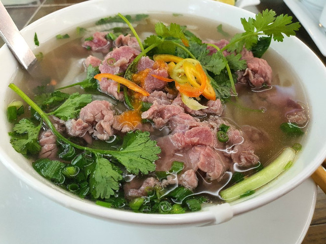Người Hà Nội hào hứng khi được ăn sáng ngay tại cửa hàng. (Nguồn: Vietnam+) Hà Nội: Hàng quán đông khách, vẫn còn nhiều nơi chưa đảm bảo giãn cách ảnh 1