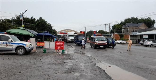 Lực lượng chức năng điều phối giao thông, hướng dẫn người dân vào làm thủ tục tại chốt Tân Lập, huyện Đồng Phú sáng 17/10. (Ảnh: Sỹ Tuyên/TTXVN) Thêm một số địa phương công bố cấp độ dịch COVID-19 ảnh 2