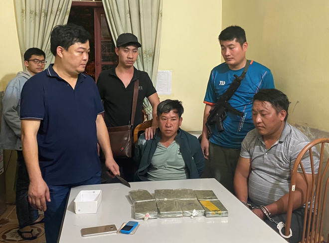 Hai đối tượng bị bắt giữ và tang vật. (Ảnh: TTXVN phát) Sơn La: Bắt quả tang 2 đối tượng vận chuyển 8 bánh heroin ảnh 1