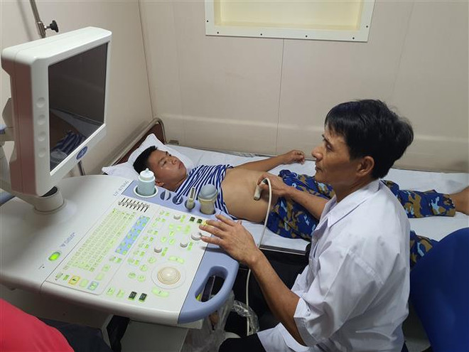 Thiếu tá Trần Văn Ngọc, phụ trách Quân y tàu 561 khám bệnh cho chiến sỹ. (Ảnh: Nguyễn Cúc/TTXVN) Bệnh viện nổi 561 Hải quân và hải trình đến Trường Sa đầy sóng gió ảnh 2