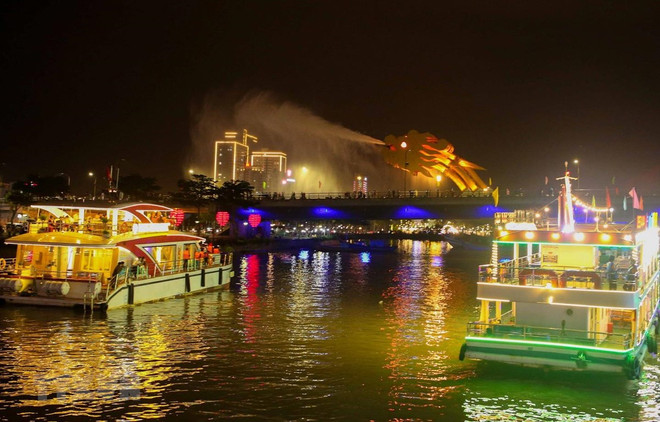 Các du thuyền đưa du khách ngắm cầu Rồng phun nước trong tour du lịch miễn phí thưởng ngoạn ngắm sông Hàn về đêm. (Ảnh: Trần Lê Lâm/TTXVN) Nhiều sản phẩm du lịch mới nhằm thu hút du khách đến Đà Nẵng ảnh 1