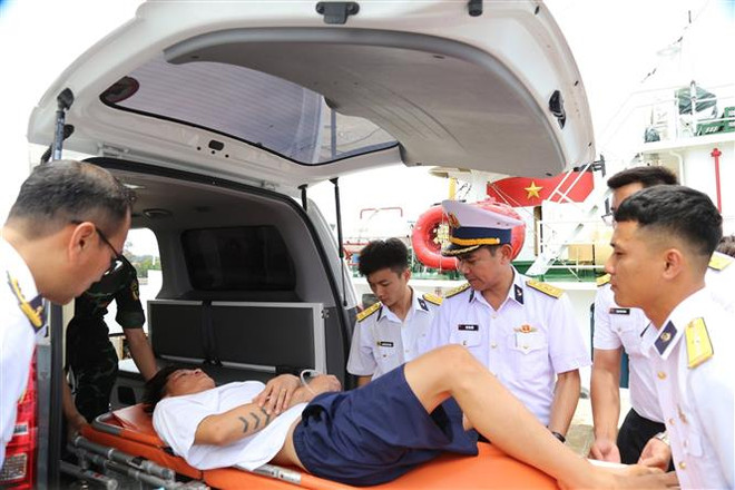 Các lực lượng hải quân đưa ngư dân gặp nạn vào bờ điều trị an toàn. (Ảnh: TTXVN phát) Vùng 4 Hải quân bàn giao 2 ngư dân bị nạn vào đất liền điều trị ảnh 1