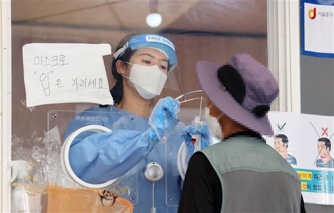 Nhân viên y tế lấy mẫu xét nghiệm COVID-19 cho người dân tại Seoul, Hàn Quốc. (Ảnh: YONHAP/TTXVN) Các nước thực hiện nhiều biện pháp nghiêm ngặt hơn nữa chống COVID-19 ảnh 1