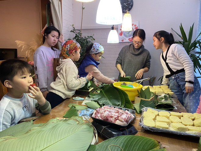 Các cháu nhỏ tập trung học cách gói bánh chưng. (Ảnh: Thành Long/TTXVN) Người Việt tại Bỉ rộn ràng sắm Tết Nguyên đán Quý Mão 2023 ảnh 1
