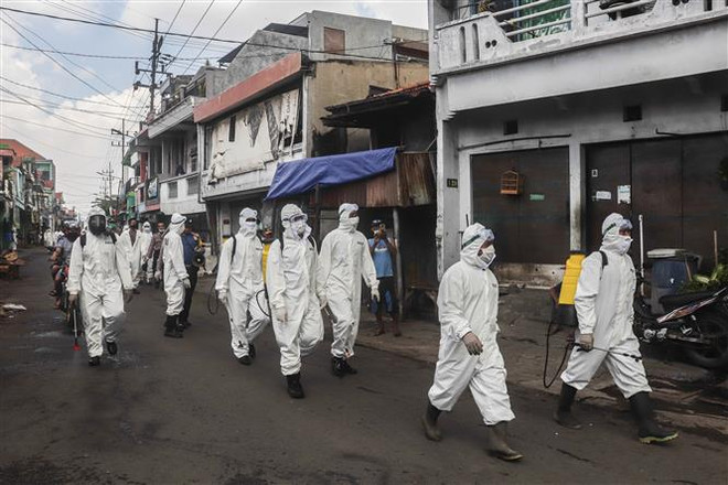 Quân đội và cảnh sát Indonesia tham gia phun thuốc khử trùng phòng lây lan dịch COVID-19 tại Surabaya, ngày 16/4/2020. (Ảnh: THX/TTXVN) COVID-19: Indonesia vượt quá 7.000 ca, Singapore gia hạn phong tỏa ảnh 1