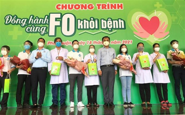 Hội Thầy thuốc trẻ Thành phố Hồ Chí Minh cùng lãnh đạo quận Phú Nhuận tặng hoa và quà cho đội hình Đồng hành cùng F0 khỏi bệnh. (Ảnh: Thanh Vũ/TTXVN) F0 khỏi bệnh ở lại tuyến đầu: Những tình nguyện viên F0 đặc biệt ảnh 1