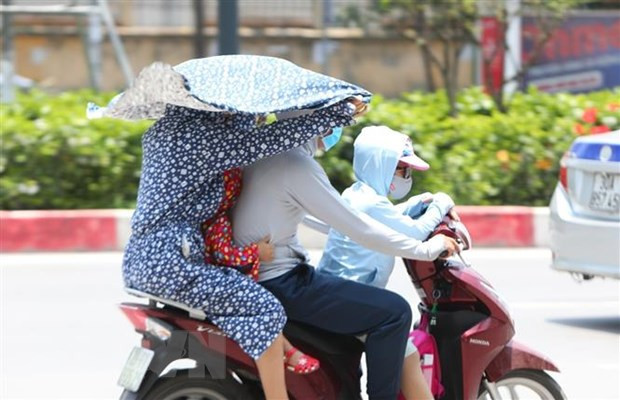 Người dân tìm mọi cách tránh nắng khi tham gia giao thông. (Ảnh: Thành Đạt/TTXVN) Khu vực Bắc Bộ và Trung Bộ sắp có nắng nóng trên diện rộng ảnh 1