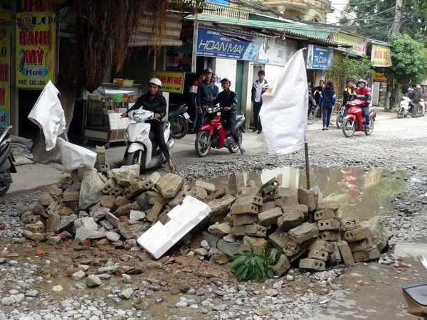 Các phương tiện tham gia giao thông gặp rất nhiều khó khăn khi lưu thông qua tuyến đường bị hư hỏng nặng bị người dân chặn gạch đá ở giữa đường. (Ảnh: Tá Chuyên/TTXVN) Người dân tại thành phố Vinh tự ý lập chốt chặn xe tải trọng lớn ảnh 1