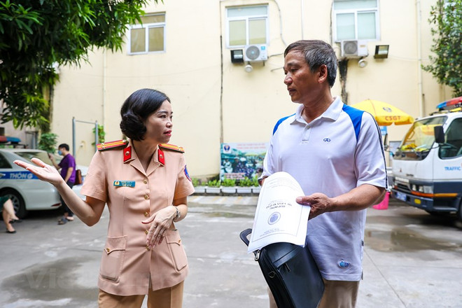 Người dân đang được cán bộ nơi đăng ký xe hướng dẫn làm thủ tục sang tên đổi chủ cho phương tiện của mình trước khi được cấp biển số định danh cá nhân. (Ảnh: PV/Vietnam+) 'Chợ' kinh doanh xe cũ ra sao sau khi áp dụng định danh biển số? ảnh 2