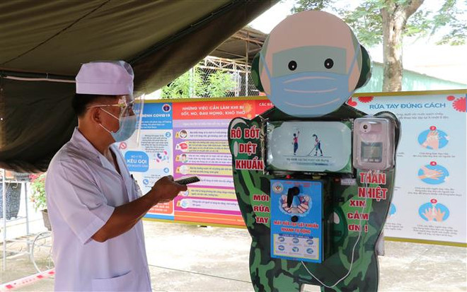 Thiếu tá Lê Mạnh Hùng với sản phẩm robot rửa tay, sát khuẩn. (Ảnh: Hồng Điệp/TTXVN) Thiếu tá quân đội sáng chế robot rửa tay, sát khuẩn chống COVID-19 ảnh 1