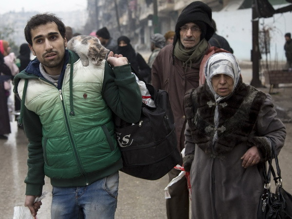 Người dân Syria sơ tán khỏi các khu vực do quân nổi dậy kiểm soát để đến các khu vực đã được quân Chính phủ giải phóng ở Aleppo ngày 13/12. (Nguồn: AFP/TTXVN) Dân quân ủng hộ Tổng thống Assad ngăn hoạt động sơ tán ở Aleppo ảnh 1