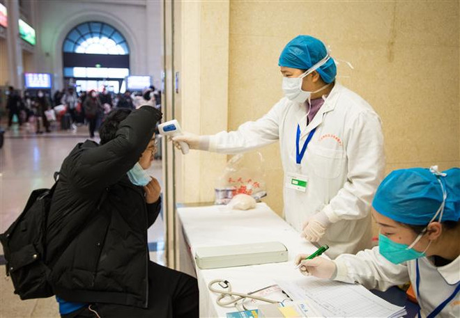 Nhân viên y tế kiểm tra thân nhiệt của hành khách tại một nhà ga ở Vũ Hán, thủ phủ tỉnh Hồ Bắc, Trung Quốc ngày 22/1/2020. (Ảnh: THX/TTXVN) Vắcxin ngừa chủng corona mới có thể được thử nghiệm trong 3 tháng tới ảnh 1